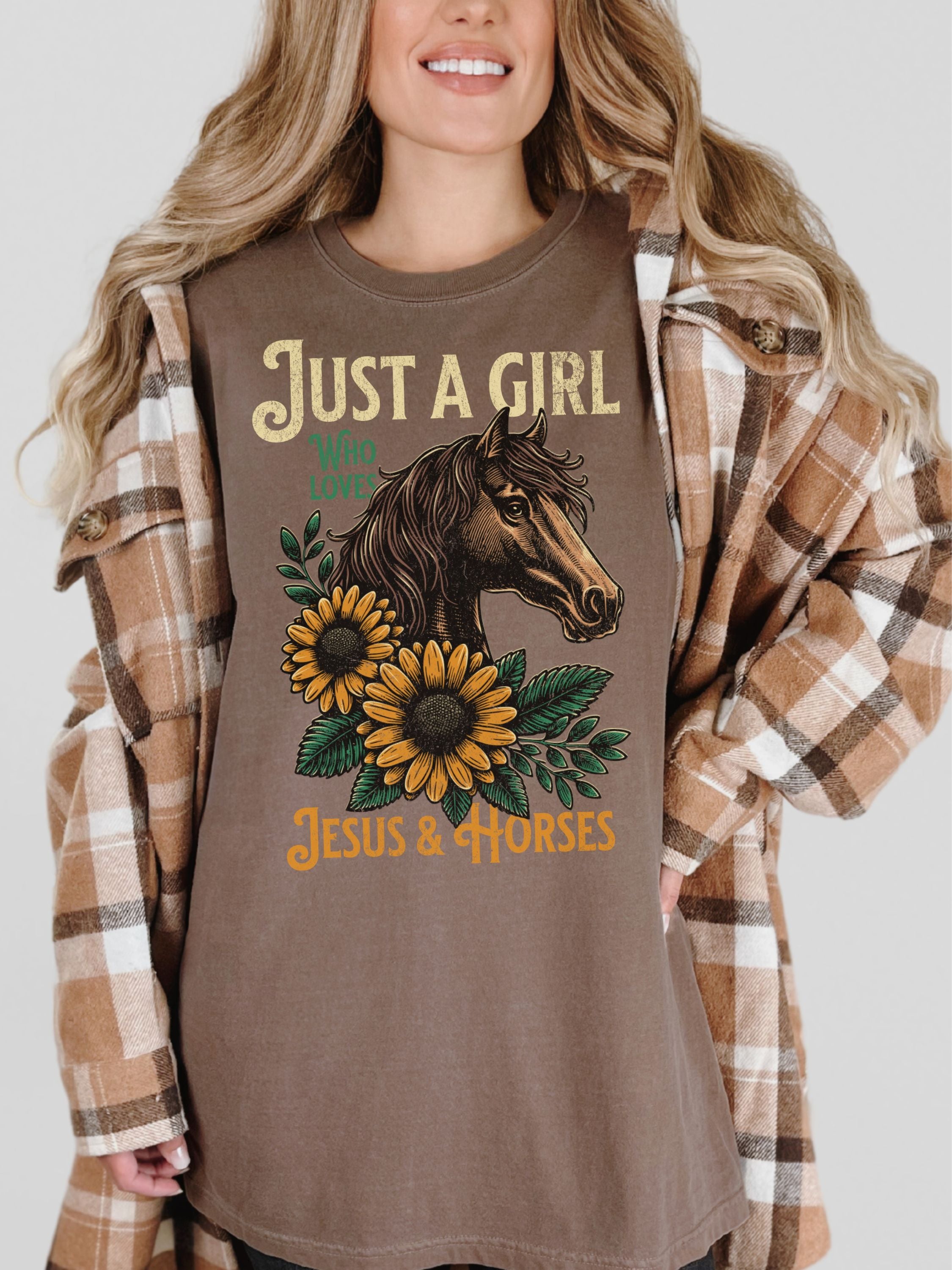 Woman wearing a brown t-shirt with a horse and sunflower design, text 'Just a Girl who loves Jesus & Horses', and plaid shirt.