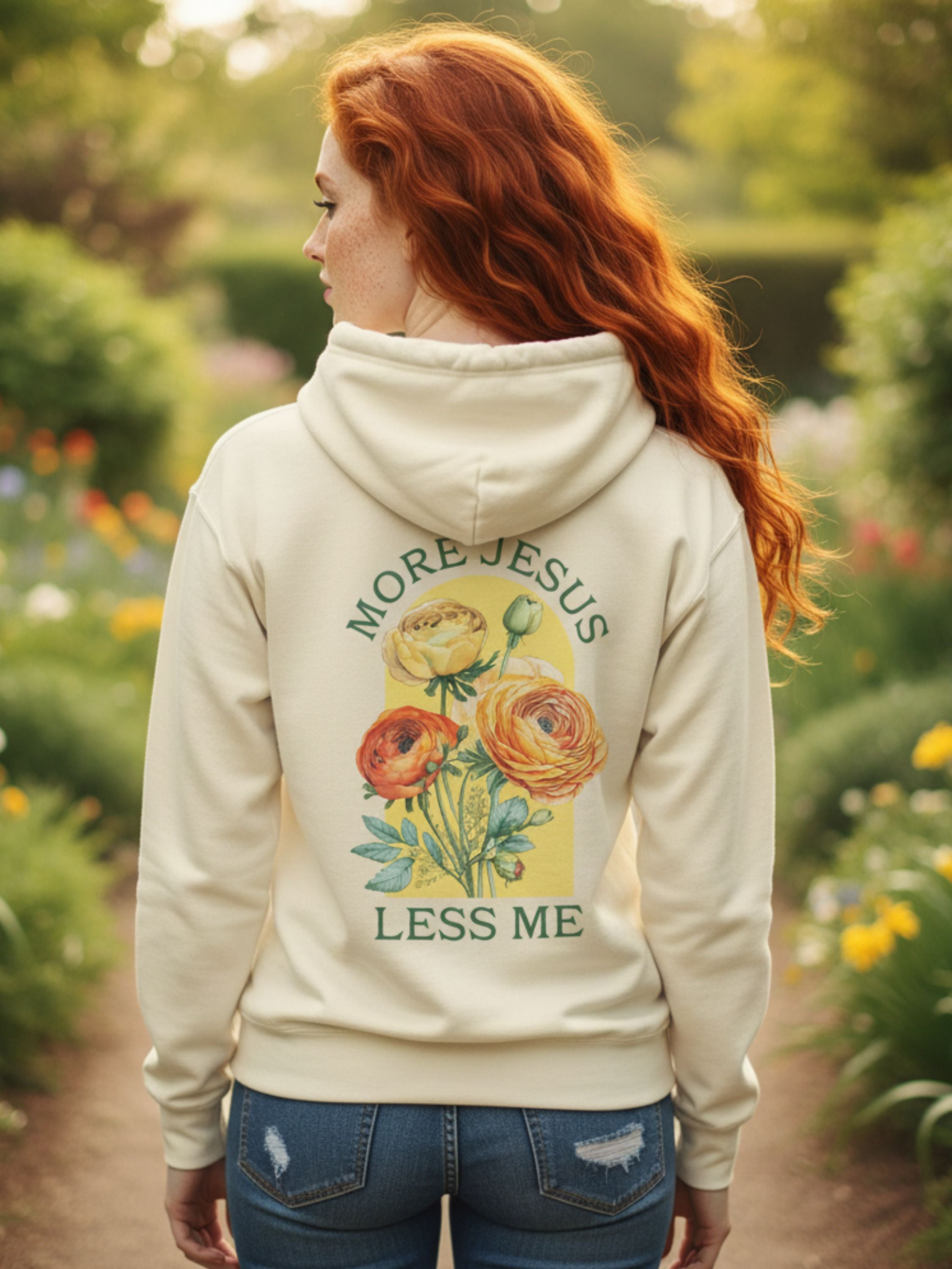 Person wearing a hoodie with floral design and text in a garden